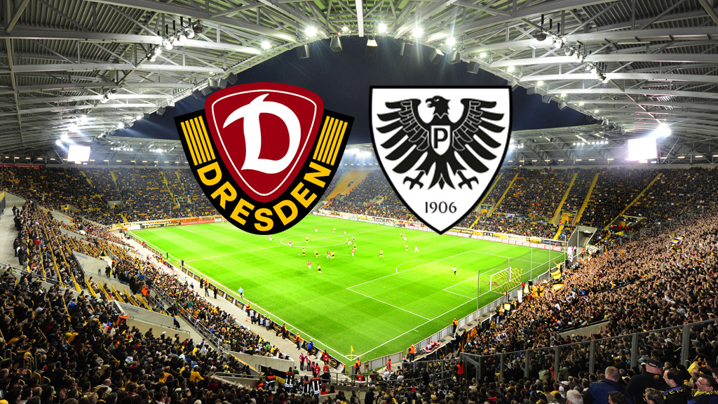 Ein breites, horizontales Bild zeigt ein Fußballstadion, das voll von Fans ist, die gelbe Trikots tragen. Auf dem Spielfeld sind Fußballspieler zu sehen. Am oberen Rand des Bildes, in der Mitte, befinden sich zwei Logos. Das linke Logo ist das Wappen von Dynamo Dresden, das rechte Logo ist das Wappen des SC Preußen Münster.